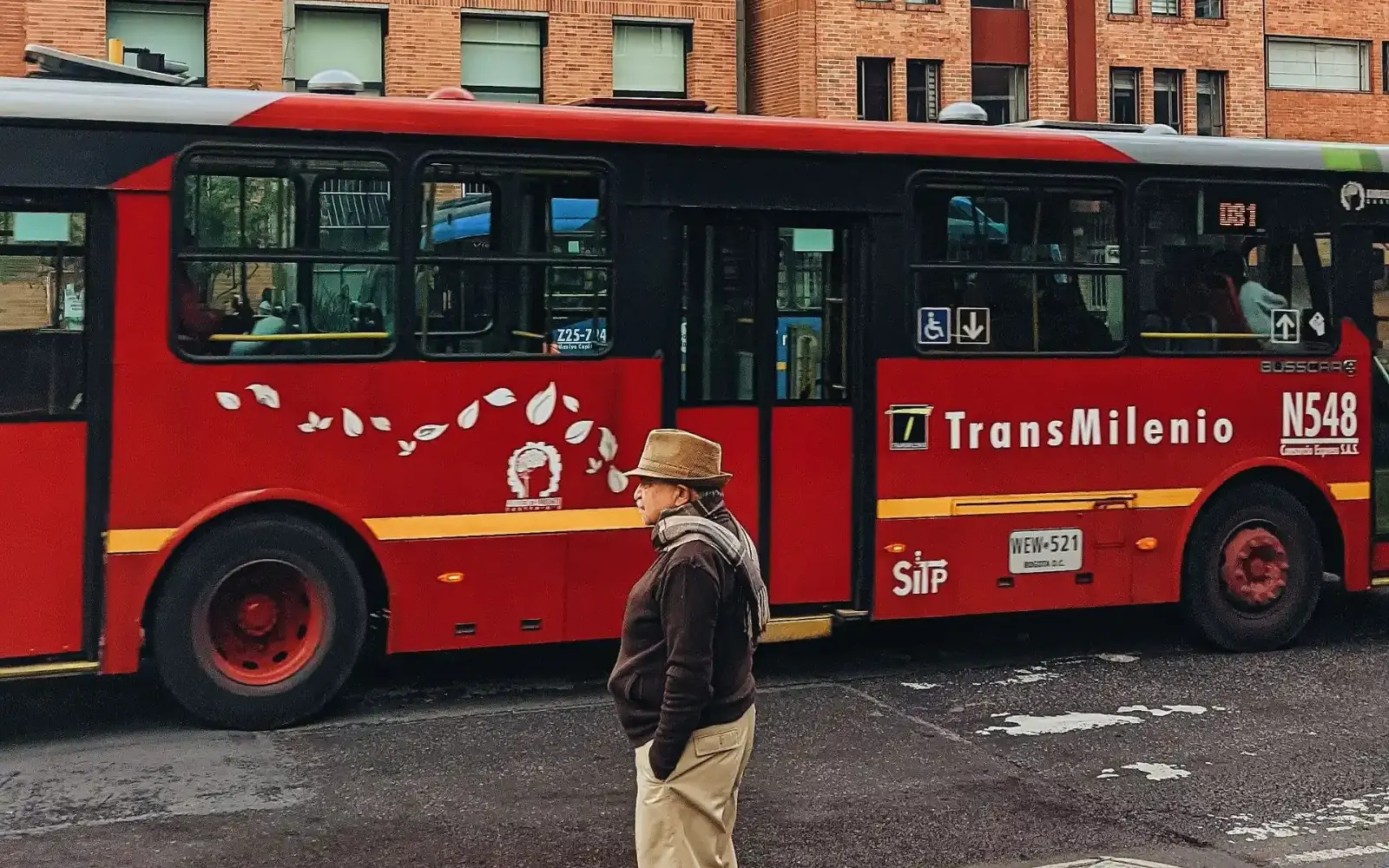 Conductor junto a un bus de TransMilenio en una calle de Bogotá