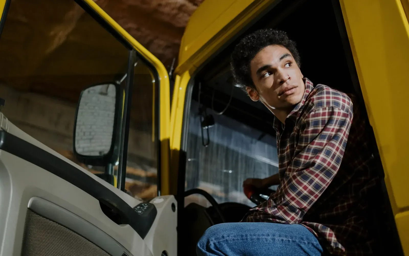 Joven conductor en la cabina de un camión amarillo