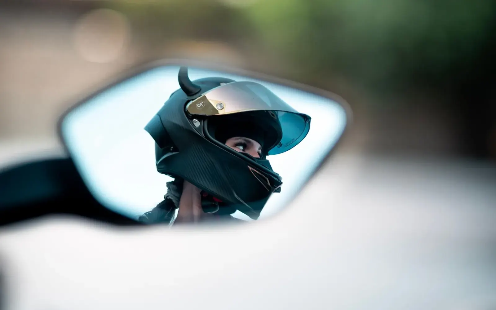 Motociclista con casco visto a través del espejo retrovisor